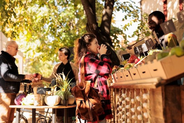 A wide shot of a bustling local farmers market in the USA, with vendors selling fresh produce, artisanal cheeses, and homemade goods. The scene is vibrant and lively, emphasizing the sense of community and connection between local businesses and customers.