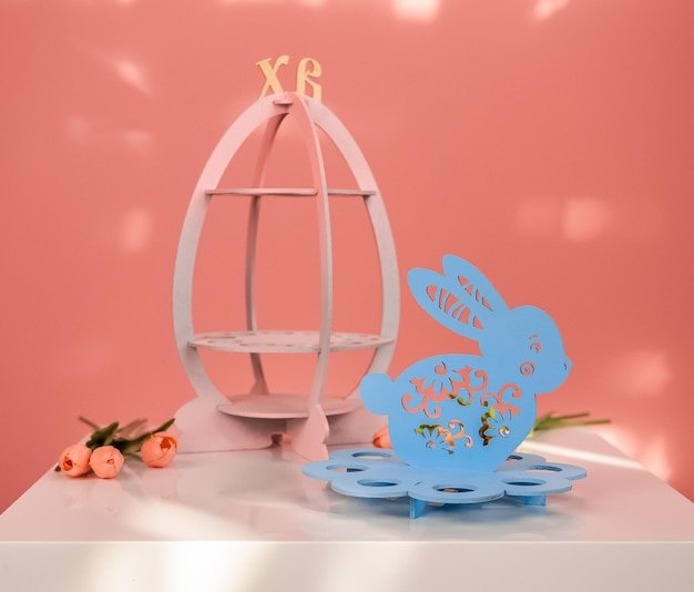 A small apartment decorated for Easter with pastel accents. A bookshelf is adorned with pastel-colored books and decorative eggs. A small coffee table holds a vase of pastel tulips and a ceramic bunny. Soft, natural light filters through the window, creating a cozy and inviting atmosphere.