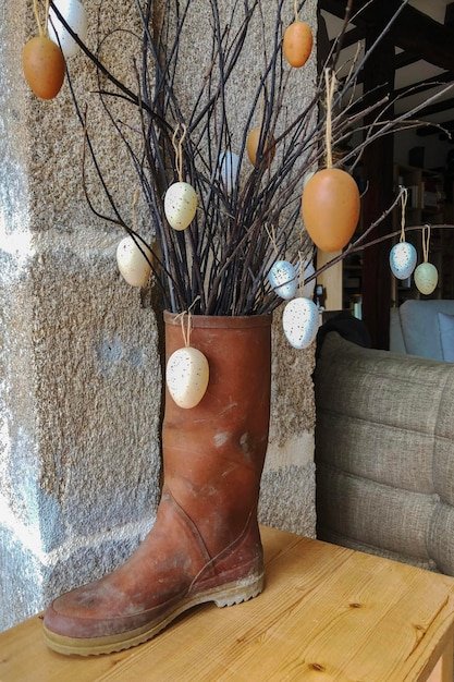 A close-up shot of a rustic Easter centerpiece featuring a wooden tray filled with moss, ceramic bunnies, and speckled Easter eggs in various pastel colors. Twine is wrapped around the tray for an added rustic touch.