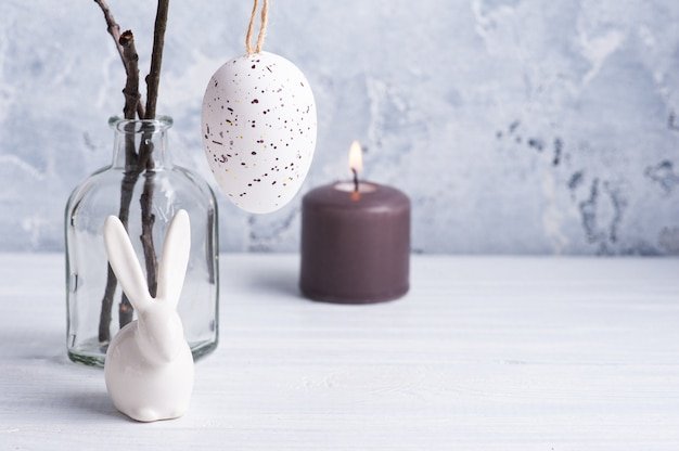 A close-up shot of a collection of naturally dyed Easter eggs in muted pastel colors such as pale grey, soft beige and light peach. The eggs are arranged in a shallow wooden bowl filled with natural straw.