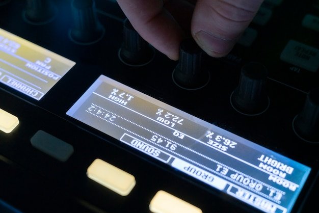 An audiophile carefully adjusting the settings on a high-end equalizer with a digital display, surrounded by various headphones and audio cables, showcasing the dedication to achieving optimal sound quality.